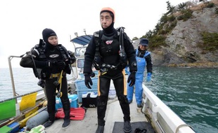 Yasuo Takamatsu (C) s'apprête à plonger à Onagawa, sur la côte est du Japon, pour tenter de retrouver sa femme disparue dans le tsunami, le 2 mars 2014