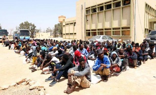 Des migrants d'Afrique subsaharienne attendent devant un centre de rétention à Misrata, dans l'est de la Libye, d'être transférés vers un autre centre, le 9 mai 2015