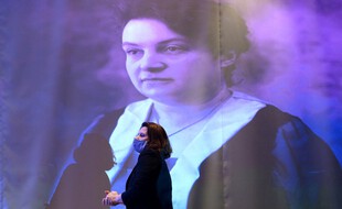 La ministre déléguée aux Sports, Roxana Maracineanu, passe devant un portrait de l'athlète et pionnière, Alice Milliat, lors de la cérémonie d'inauguration d'une statue hommage à Milliat, à la Maison du sport français qui abrite le Comite national olympique et sportif français, à Paris, le 8 mars 2021.