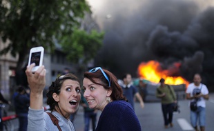 Des touristes font un selfie lors de manifestations houleuses le 1er mai 2014, à Barcelone.