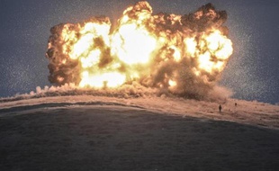 Des membres du groupe Etat islamique devant une explosion lors d'une attaque aérienne le 23 octobre 2014 sur la montagne Tilsehir (Syrie)