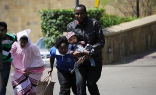 Un policier escorte des personnes qui quittent un centre commercial de Nairobi, dans lequel se déroule une prise d'otages, le 21 septembre 2013