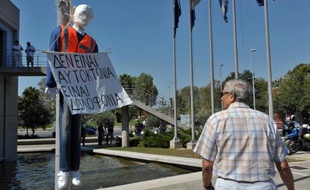 Un homme grec passe près d'un mannequin déguisé en gardien d'école et portant une pancarte "ce n'est pas un suicide, c'est un meurtre", après le licenciement de fonctionnaires le 7 septembre 2013 à Thessalonique