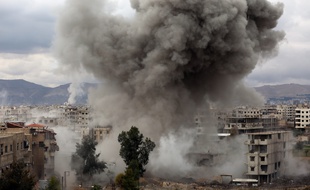 De la fumée s'échappe de bâtiments pilonnés par l'armée syrienne, à Kafr Batna, dans l'enclave rebelle de la Ghouta, près de Damas, le 22 février 2018.