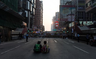 Deux personnes assises devant des barricades tenues par des manifestants pro-démocratie à Hong Kong, le 5 octobre 2014.