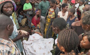 Des personnes se tiennent près d'une fosse après le massacre de 22 personnes par des rebelles ougandais, le 20 octobre 2014 à Beni, dans l'est de la RDC