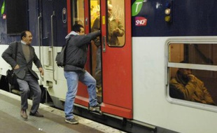 Un homme tente de monter à bord d'un RER à Paris.