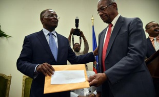 François Benoit (d), le président de la commission électorale indépendante présente son rapport recommandant l'annulation du premier tour de le présidentielle en présence du président provisoire Jocelerme Privert (g) à Port-au-Prince, le 30 mai 2016