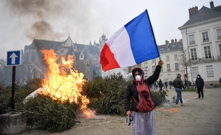 Un manifestant devant un tas de sapins incendié en marge d'un défilé de «gilets jaunes» à Nantes.
