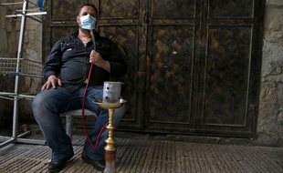 Un homme qui fume la chicha sous son masque