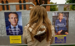 Une citoyenne devant les affiches de campagnes de Marine Le Pen et d'Emmanuel Macron . Le 29/04/ 2017.AFP PHOTO/PHILIPPE HUGUEN