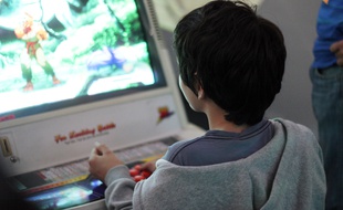 Illustration d'un enfant jouant dans une salle d'arcade reconstituée près de Rennes lors d'un événement dédié au jeu vidéo.