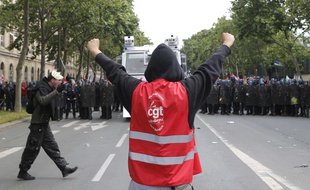Un manifestant portant un gilet de la CGT face des à agents des forces de l'ordre lors du défilé contre la loi travail le 14 juin 2016 à Paris.