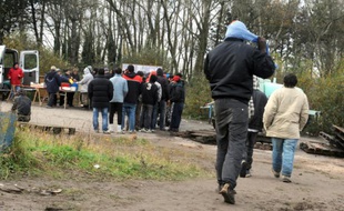 Des membres d'une association humanitaire distribue des repas à des migrants afghans, kurdes, iraniens, érythréens et vietnamiens dans le camp de Téteghem près de Dunkerque, le 18 novembre 2010