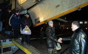 Image diffusée par le service de presse de la présidence ukrainienne du président Petro Poroshenko (d) accueillant des militaires ukrainiens venant d'être libérés, près de Kiev, le 27 décembre 2014