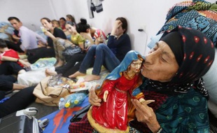 Une femme chrétienne irakienne fuyant la violence du village de Qaraqush, dans le nord du pays, embrasse une statue de la vierge dans un centre de réfugiés d'Arbil, le 27 juin 2014