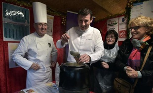 Les chefs français Pascal Bastian (C) et Emile Jung (G) servent une soupe au marché de Noël à Strasbourg, le 27 novembre 2015