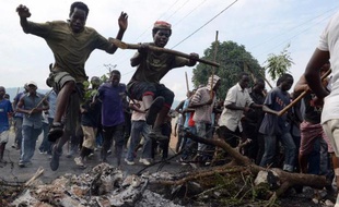 Des manifestants burundais opposés à un troisième mandat du président Pierre Nkurunziza sautent par dessus les cendres d'une barricade, le 1er mai 2015 à Bujumbura