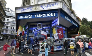 Des personnes se promènent devant des marchands de souvenirs à Lourdes en France, le 15 août 2015