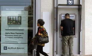 Un Grec en train de tirer de l'argent à un distributeur alors que la question de la sortie de la Grèce de la zone euro se pose.