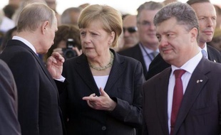 La chancelière allemande Angela Merkel s'entretient avec le président russe Vladimir Poutine (g) et le président élu ukrainien Petro Poroshenko (d) à Ouistreham en Normandie lors des commémorations du 70e anniversaire du Jour J, le 6 juin 2014