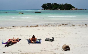 Des touristes bronzent sur une plage de l'île de Praslin aux Seychelles le 6 mars 2012