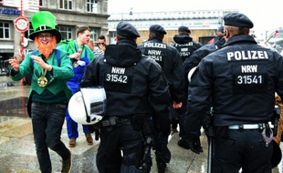 Un festivalier déguisé en bouffon fête le début du carnaval de Cologne, en Allemagne, près de policiers, le 4 février 2016