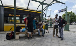 Un groupe de migrants attend un tram dans la ville hongroise de Szeged le 3 août 2015 après avoir franchi la frontière entre la Serbie et la Hongrie