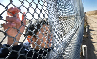 Un enfant regarde à travers le grillage de la frontière entre le Mexique et les Etats-Unis, le 24 décembre 2013.