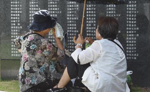 Des Japonaises se recueillent au pied d'un monument de marbre noir où sont inscrits les noms des défunts, le 23 juin 2015 à Okinawa