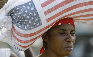 Une femme porte un sac de riz donné par l'Usaid, en Haiti, le 16 janvier 2010.