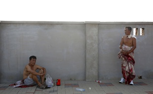 Des hommes patientent en attendant d'être pris en charge par les secours, après les explosions à Tianjin, en Chine, dans la nuit du 12 au 13 août.