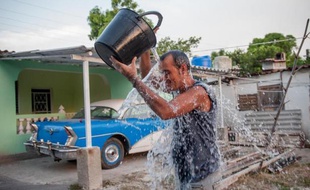Un cubain se rafraîchit avec un seau d'eau dans une rue de La Havane, le 27 août 2014 alors que le pays est frappé par la canicule