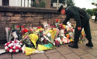 Un officier de la Royal Ulster Constabulary dépose des fleurs devant le site d'un attentat à Omagh le 17 août 1998