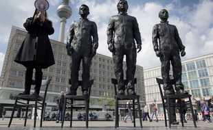 Berlin, le 1er mai 2015. Une femme prononce un discours aux côtés des sculptures de l'artiste italien Davide Dormino représentant les lanceurs d’alerte Chelsea Manning, Julian Assange et Edward Snowden.