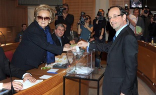 Le député socialiste François Hollande, s'apprête à déposer son bulletin de vote dans l'urne, sous le regard de Bernadette Chirac, le 31 mars 2011 à l'Hôtel du département de Tulle, en Corrèze.