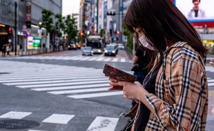 Une femme, suspendue à son téléphone, se promène dans la rue à Tokyo