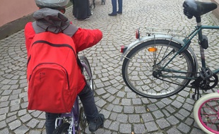Un enfant à vélo portant un casque devant une école du centre de Strasbourg