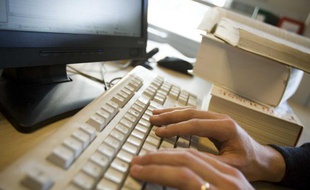 Un homme pianote sur un clavier d'ordinateur.