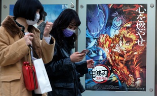 Le 16 décembre 2020, à Tokyo (Japon), deux femmes passent devant l'affiche du film Demon Slayer, plus grand succès de tous les temps dans les salles japonaises.