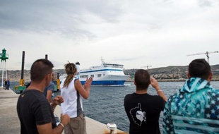 Des employés de la SNCM en grève applaudissent le 4 juillet 2014 lors de l'arrivée du bateau "Jean Nicoli" dans le port de Marseille après son départ de Porto-Vecchio à la suite de heurts avec des commerçants corses