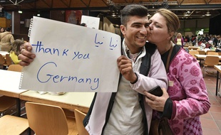 Un réfugié venu d'Afghanistan accueilli par un baiser et brandissant une bannière «Merci, l'Allemagne» à son arrivée à Dortmund, en train, le dimanche 6 septembre 2015.