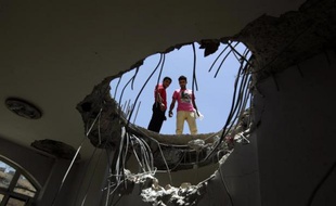 Des Yéménites regardent à travers le toit d'une maison éventrée la veille par une frappe aérienne de la coalition arabe, le 21 avril 2015 à Sanaa, près de la base de missiles de Fajj Attan