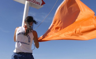 Une maître nageur sauveteur hisse le drapeau orange sur une plage de Marseille.