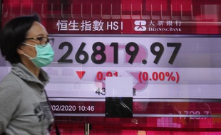 Une femme passe devant la Bourse de Hong Kong le 27 février 2020.