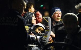Des policiers solvènes enregistrent les migrants à bord d'un bus le 21 octobre 2015 à Brezice en Solvénie