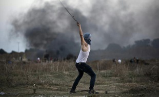 Un Palestinien lance une pierre en direction de l'armée israélienne dans la ville de la bande de Gaza de Bureij, le 15 octobre 2015