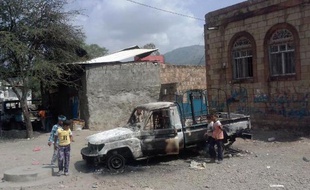 De jeunes yéménites regardent une voiture brûlée lors d'une attaque menée par des militants présumés d'Al-Qaïda contre la ville d'Udayn, sous-préfecture de la province d'Ibb, dans le sud-ouest du Yémen, le 16 octobre 2014