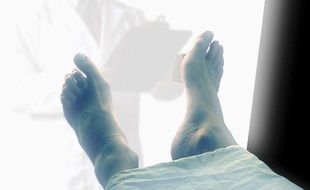 Un médecin légiste observe un cadavre.