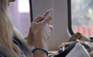 Une jeune femme utilise un smartphone dans un train.